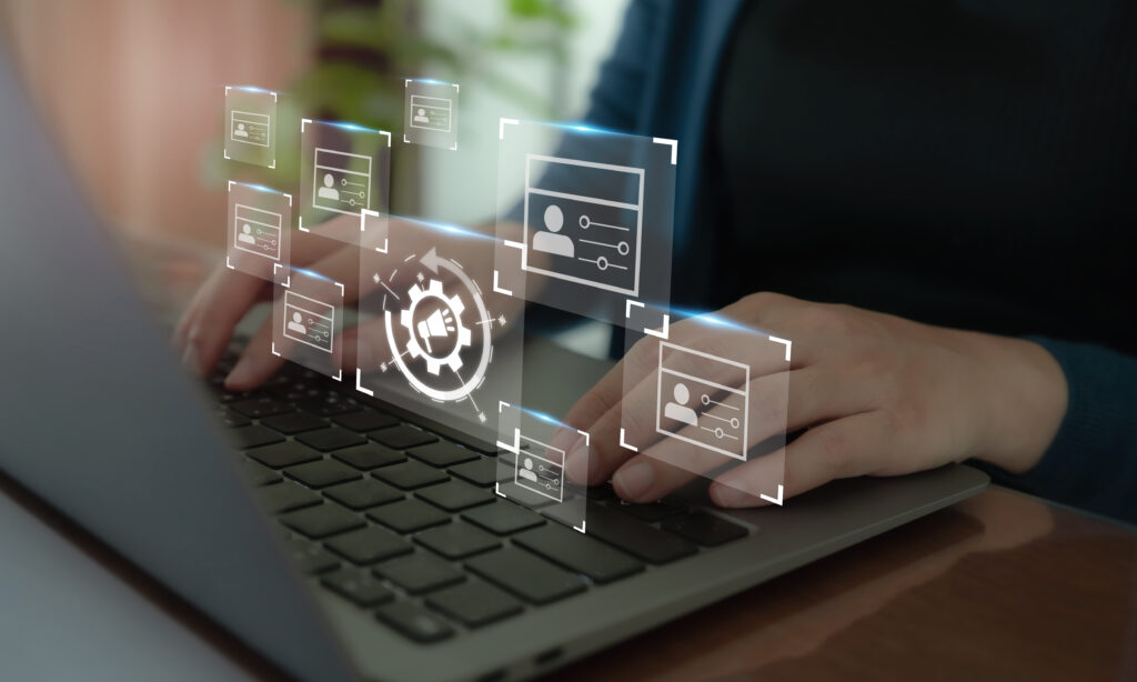 Person arbeitet am Laptop mit eingeblendeten Symbolen für Benutzerverwaltung und Systemeinstellungen – Darstellung von IT-Automatisierung und Managed Services.