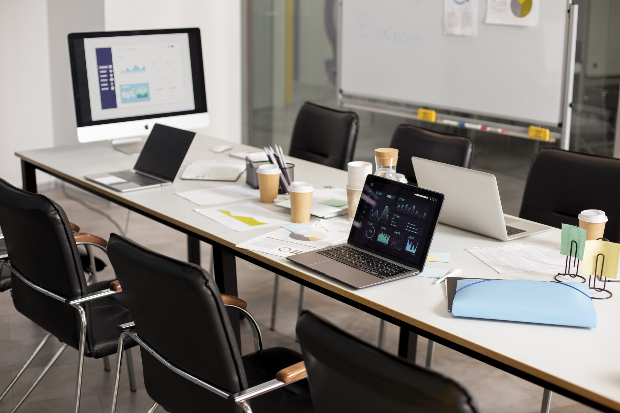 Moderner Konferenztisch mit Laptops, Monitoren, Business-Diagrammen und Teamunterlagen – Symbol für den vernetzten Modern Workplace