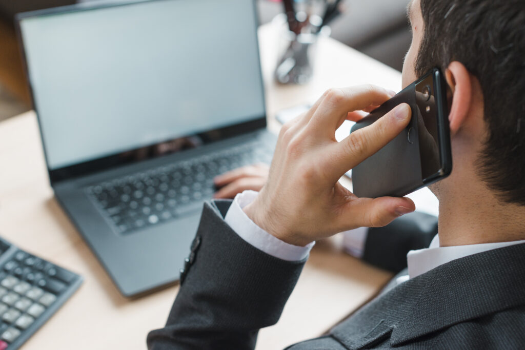 Geschäftsmann telefoniert mit dem Smartphone vor Laptop