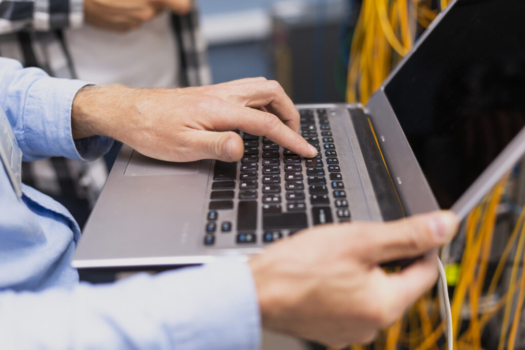 Techniker in weißem Kittel analysiert Hardwarekomponenten mit Tablet neben geöffnetem Rechner