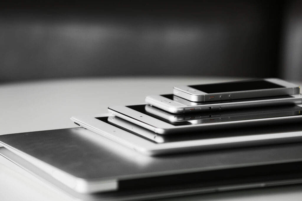 Gestapelte Smartphones, Tablets und Laptops auf einem Tisch