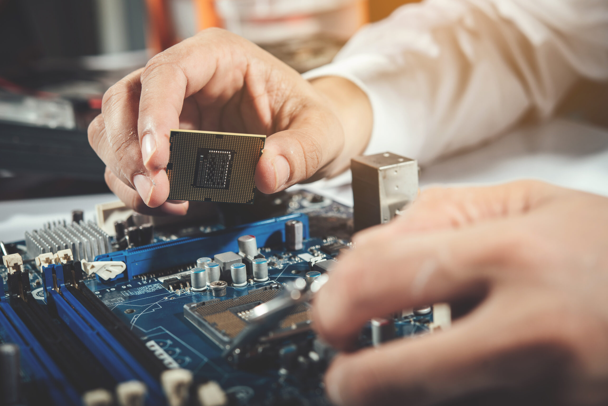 IT-Techniker setzt einen Prozessor auf ein Mainboard, Detailaufnahme bei der Wartung