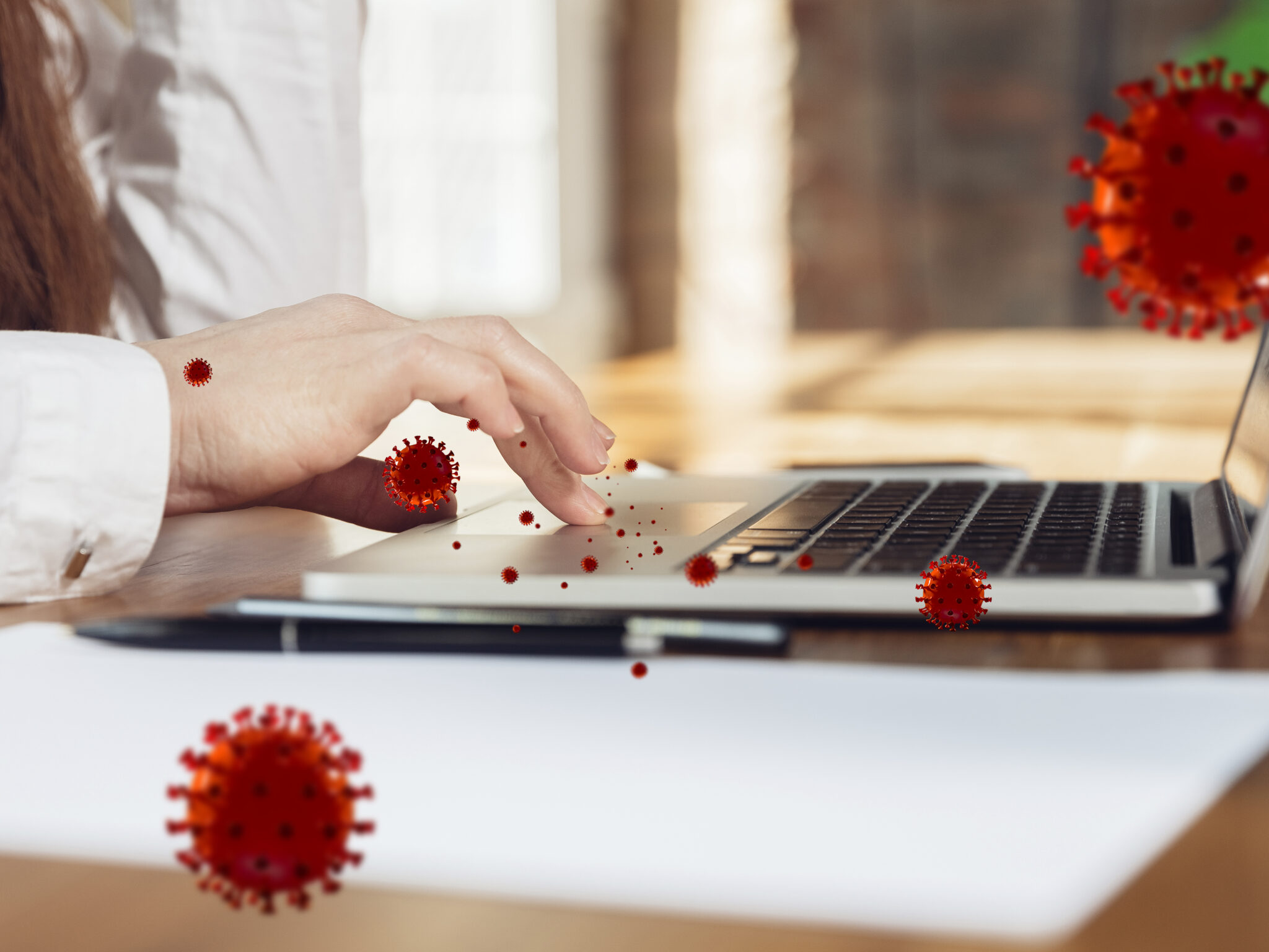 Hand an Laptop mit visualisierten Viren