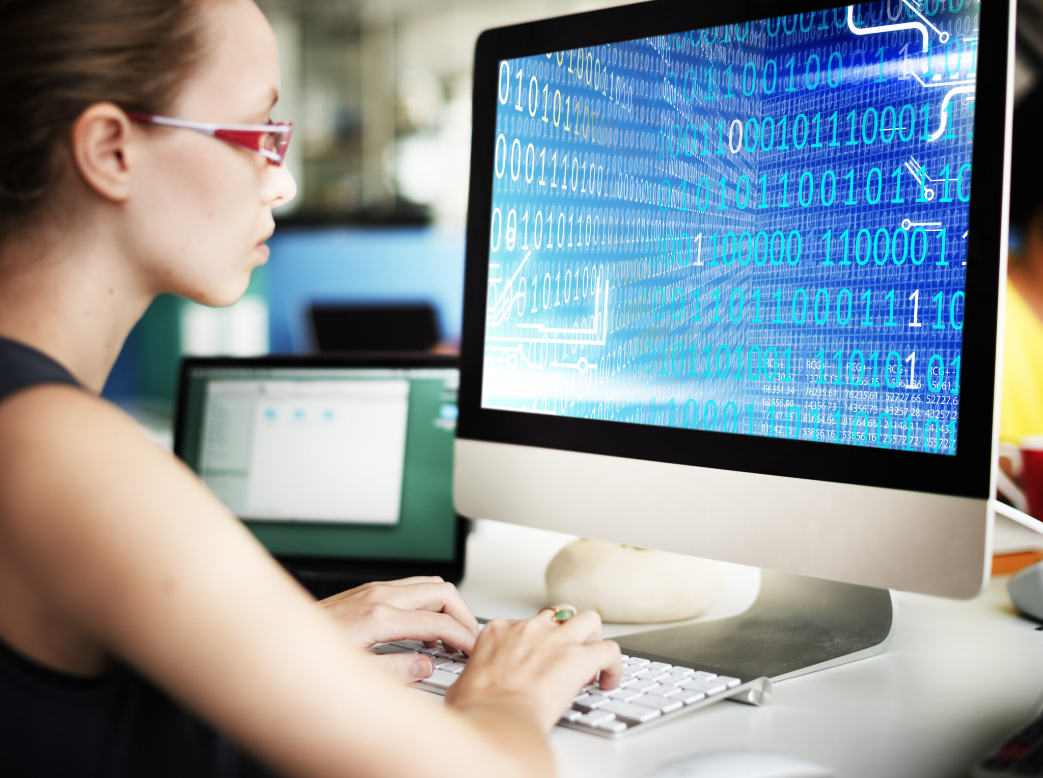 Technikerin arbeitet an Mainboard mit Werkzeugen und Laptop im Hintergrund
