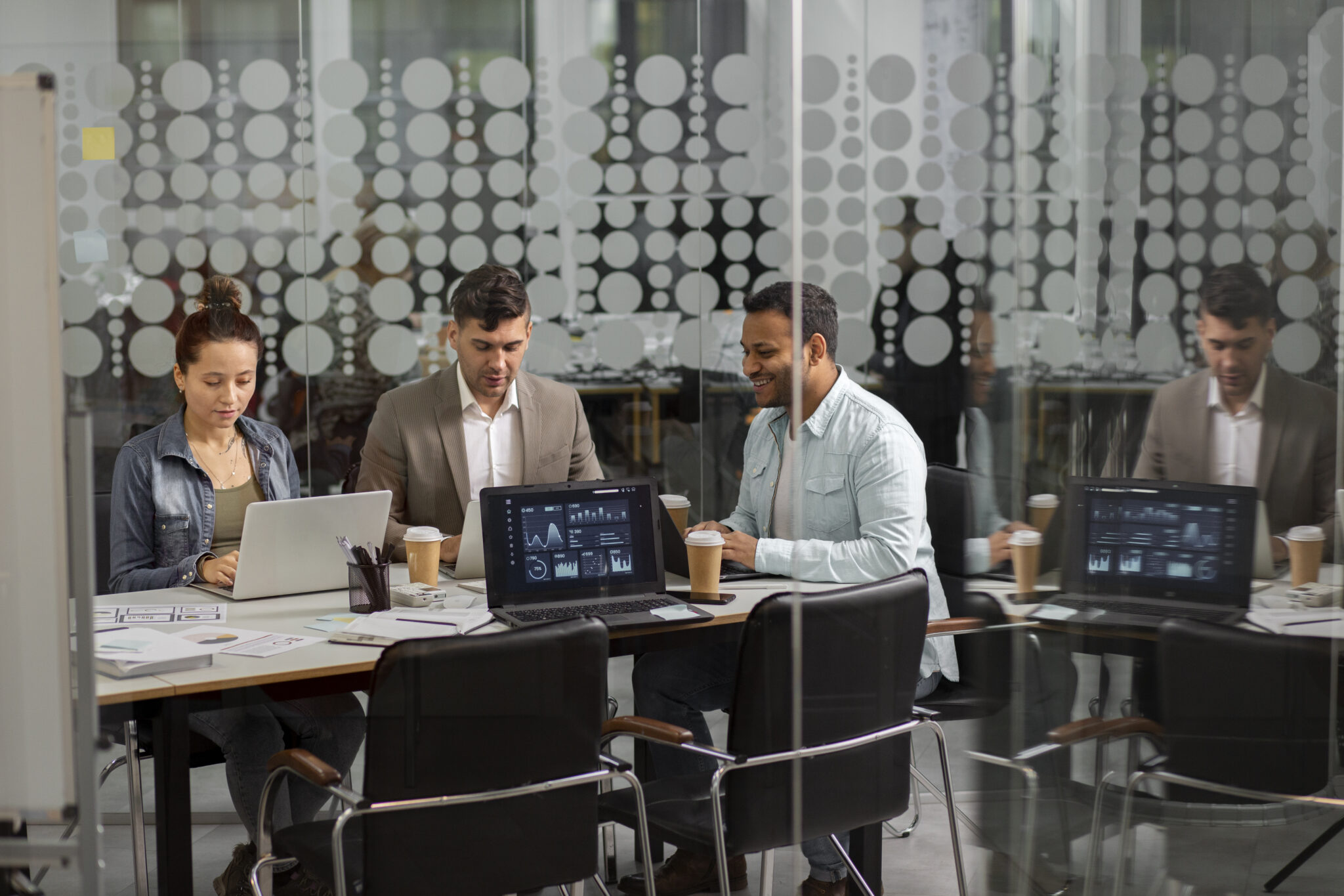 Blick von oben auf ein Team, das mit Plänen und Laptop an einem technischen IT-Projekt arbeitet