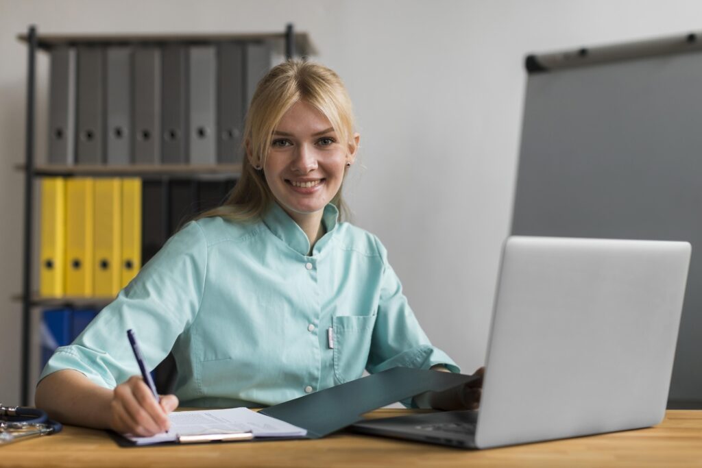 Frau im Büro am Schreibtisch mit Laptop und Unterlagen