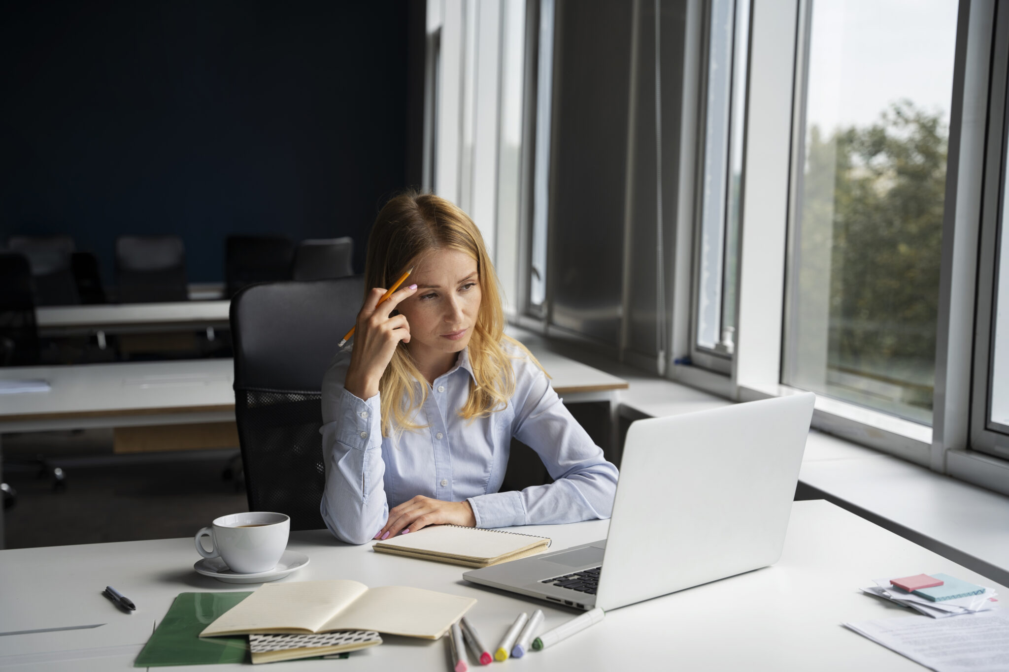 Gestresste Frau im Büro vor Laptop – Anzeichen von Burnout am Arbeitsplatz